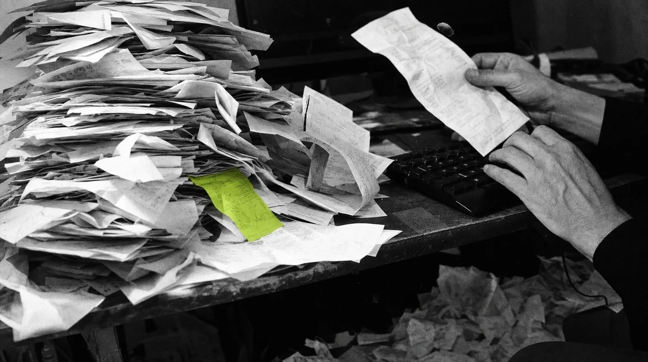 Uma pilha de faturas em papel ao lado de um teclado